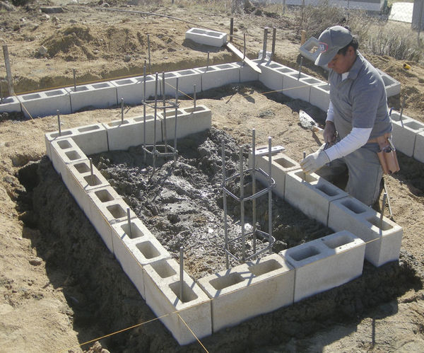 Setting Pier Blocks
Blocks are set around the perimeter of the pier footing.  Another layer of blocks will go on this layer, then the center will be filled with concrete and two sonotubes of concrete will bring the pier base up to floor level.
